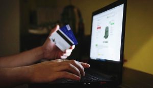 Online night shopping and paying with credit card and laptop. Man buying on an internet store in modern home office late at night. Typing login inform